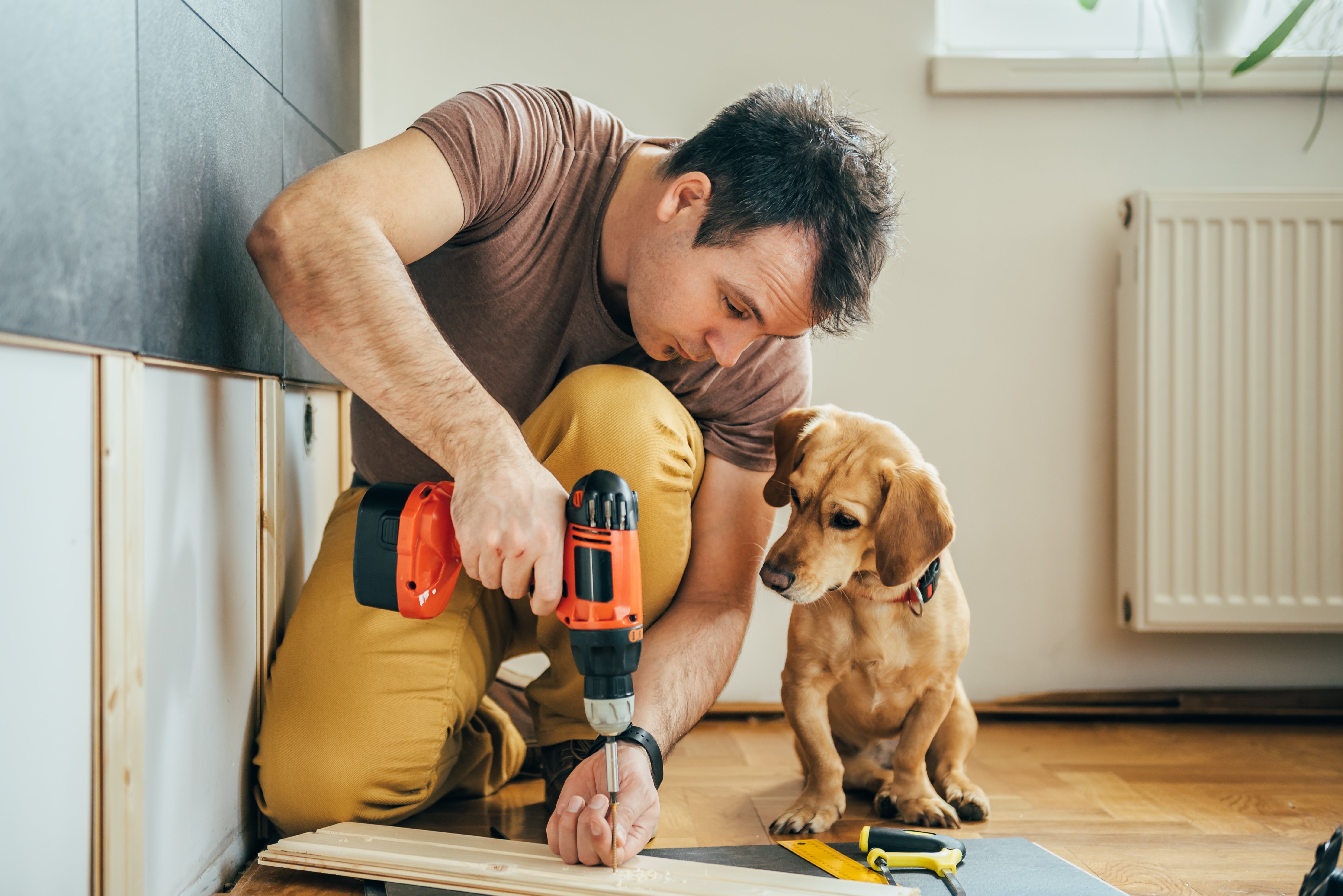 man installing flooring while a puppy watches - Contract Interiors in Fort Wayne, IN