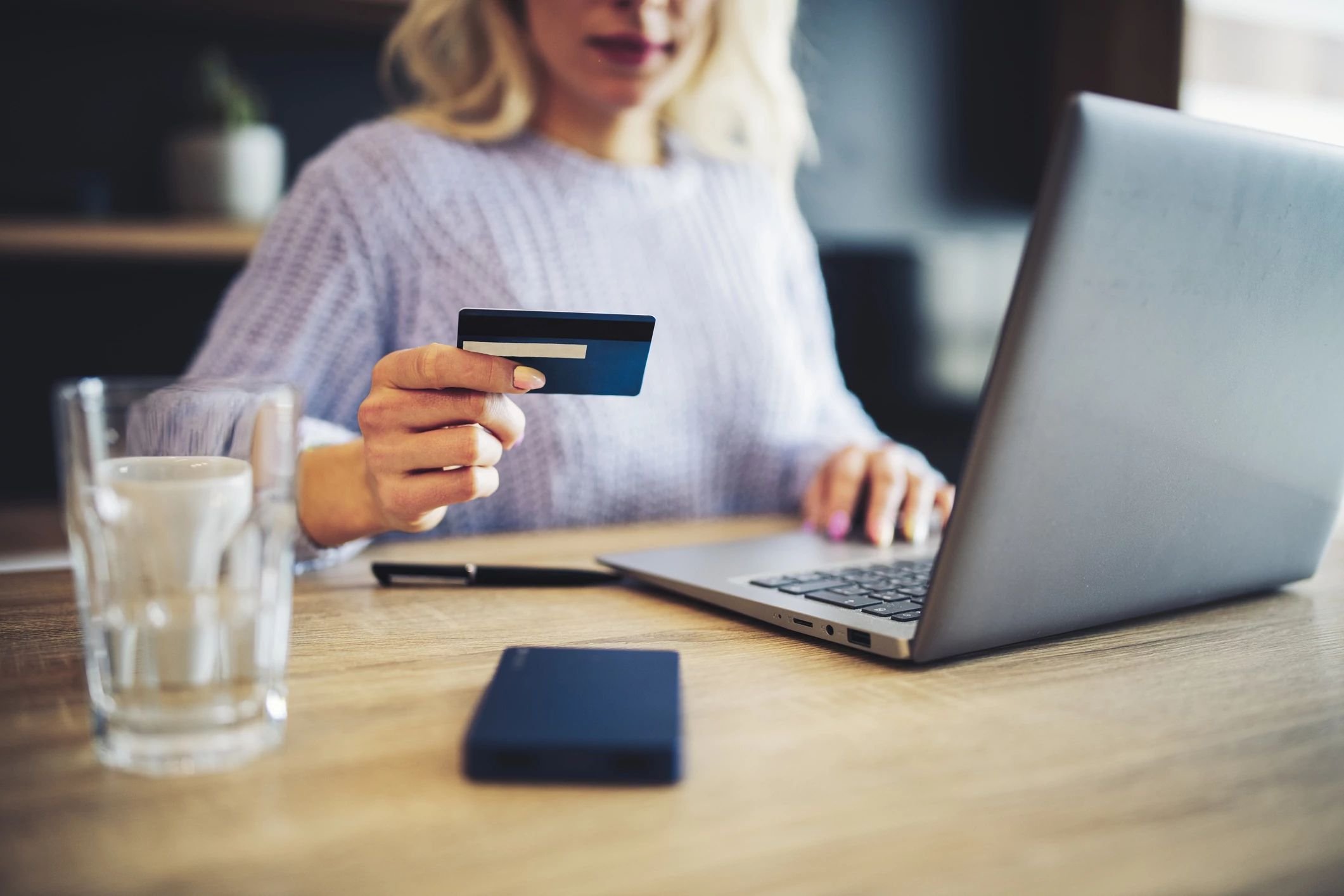 woman holding credit card and on laptop - Contract Interiors, IN